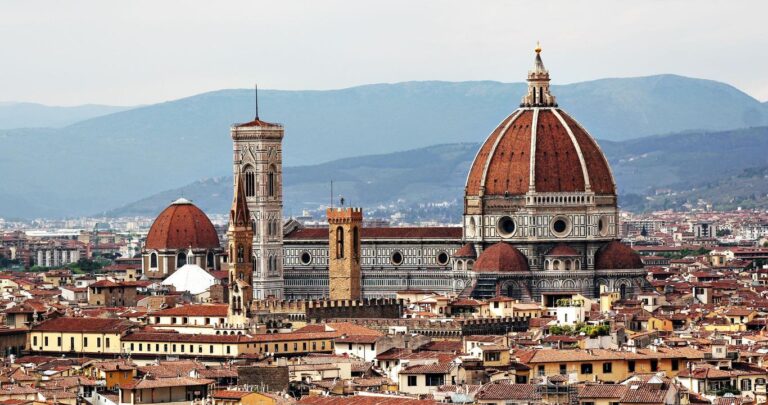 View of Florence skyline with the Cathedral of Santa Maria del Fiore and its famous dome, bell tower, and surrounding buildings. Hills are visible in the background.