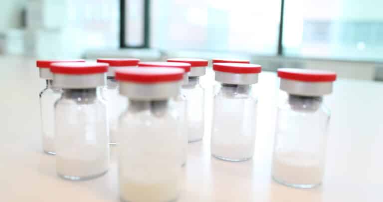 Several glass vials containing freeze-dried pharmaceutical product in a LIGHTHOUSE laboratory.